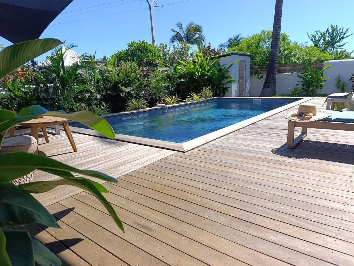 Piscine et deck en bois entourés de végétation